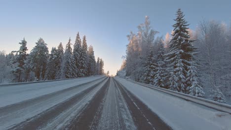 Winter-driving-POV-through-scenic-forest-landscape-with-dazzling-sunlight