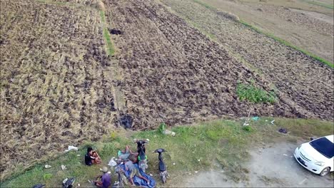 People-watch-a-drone-descend-in-front-of-rice-fields-after-harvest-in-the-morning-in-Blora,-Indonesia
