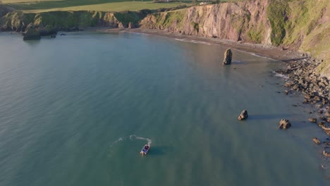 drone-cinematic-fishing-boat-working-in-Ballydwane-Bay-Copper-Coast-Waterford-Ireland-goldenhour-at-sunset