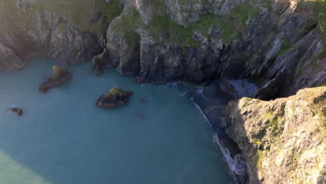 Drone-tiny-hidden-beach-under-sea-cliffs-Copper-Coast-Waterford-Ireland-at-golden-hour