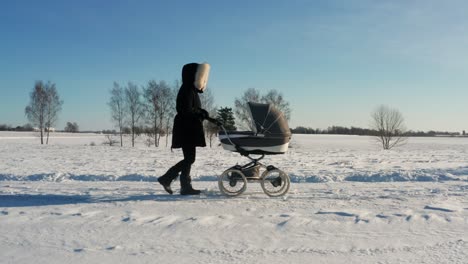 Beautiful-winter-morning-walk-with-baby-carriage,-single-mother-in-dark-jacket