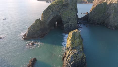 Drohnenfoto-Eines-Großen-Meeresstapels-Mit-Höhle-Und-Blauem-Meer,-Kupferküste,-Waterford,-Irland,-Schönheitsort