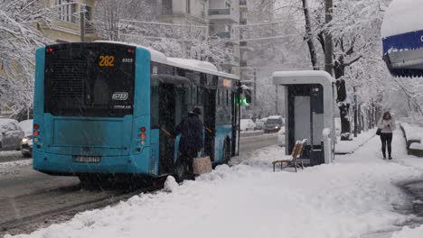 City-Bus-Arrives-At-Bus-Station-On-A-Snowy-Day