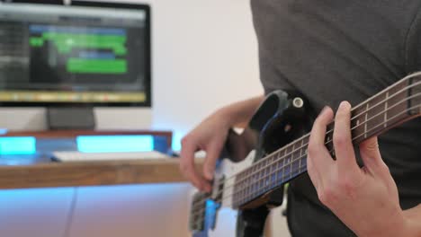 a-medium-shot-of-a-man-playing-guitar-solos,-chords-and-rhythm-with-bass-in-a-studio-focussing-on-the-hands