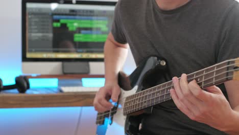 Eine-Mittlere-Aufnahme-Eines-Mannes,-Der-In-Einem-Studio-Gitarrensoli,-Akkorde-Und-Rhythmus-Mit-Bass-Spielt-Und-Sich-Dabei-Auf-Die-Hände-Konzentriert