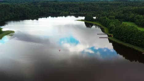 Lake-with-sky-reflection-and-Inflatable-water-toy-float,-green-forest-around