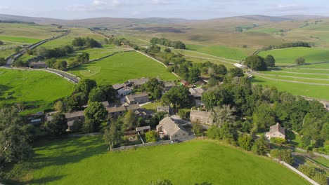 Moving,-panning-drone-footage-showing-the-beautiful-village-of-Selside-in-rural-Yorkshire,-England-with-country-lanes-dry-stone-walls,-hills,-fields-and-mountains-in-the-distance-on-a-sunny-summer-day