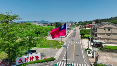 Aerial-orbiting-shot-of-waving-Taiwanese-Flag-on-Kinmen-Island-during-sunny-day-with-blue-sky
