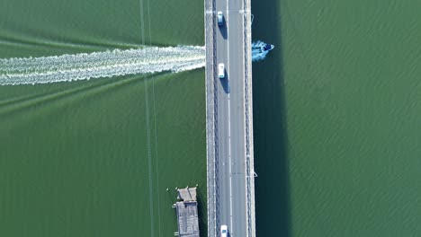 Drone-aerial-boat-under-Toukley-bridge-with-cars-travelling-on-road-transport-wharf-Gorokan-Tuggerah-Lakes-Central-Coast-tourism-Australia