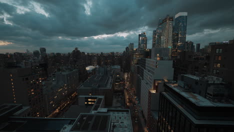Manhattan,-New-York-cityscape-at-night-from-a-penthouse-view,-featuring-cars,-people-walking,-streets,-and-the-city's-night-lights-under-a-cloudy-dark-sky