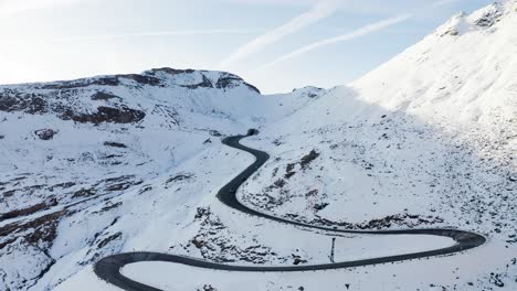 Eine-Atemberaubende-Luftaufnahme-Einer-Kurvenreichen-Straße-In-Den-Schneebedeckten-Bergen