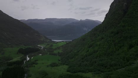 Drone-flies-through-a-valley-to-a-lake-in-Norway-surrounded-by-mountains