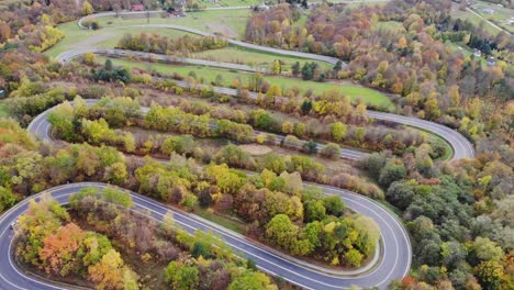 Curves-of-winding-road-through-autumn-forest-in-rural-Poland-aerial-panorama