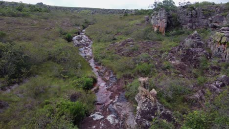 Small-river-flows-through-extremely-rugged,-eroded-rocky-landscape