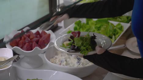 Up-close-shot-of-hands-at-salad-bar-putting-food-on-plate