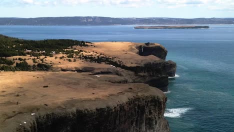 Backwards-spin-drone-shot-of-300ft-cliffs-revealing-nearby-sister-islands