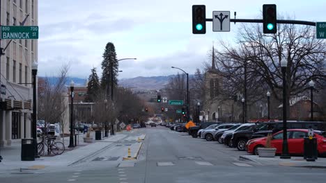 Malerische-Aussicht-Auf-Die-Straße,-Gesäumt-Von-Geparkten-Fahrzeugen-Und-Verkehr-Und-Berglandschaft-In-Der-Ferne,-Bundesstaat-Idaho,-USA