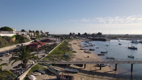 Aerial-view-of-Alvor-waterfront,-small-boats-moored-along-beach,-Algarve