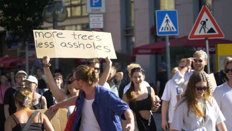 Fridays-for-Future-FFF-protest-with-activists-laughing-and-holding-funny-sign-saying-more-trees-less-assholes-in-Stuttgart,-Germany