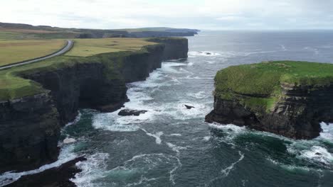 Kilkee-Cliffs-in-Ireland-with-waves-crashing-against-the-rugged-coastline,-serene-natural-beauty,-aerial-view