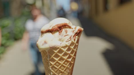 Focus-on-ice-cream-in-crispy-cone-melting-during-hot-day,-zoom-out