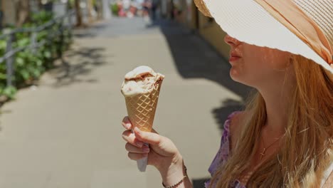 Female-tourist-with-sun-hat,-enjoying-local-ice-cream-in-crispy-cone,-Tenerife