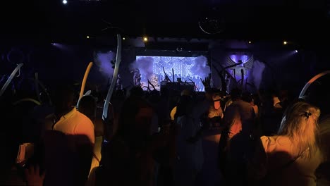 Dancers-perform-on-stage-to-people-dancing-and-waving-balloons-in-nightclub