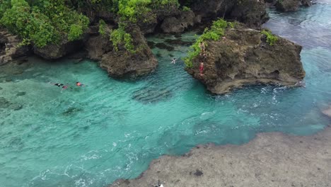 Magpupungko-rock-pools-in-Siargao-with-people-jump-and-swim-in-clear-blue-water
