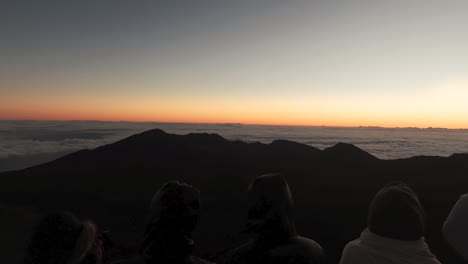People-look-out-at-horizon-from-Haleakala-Volcano-in-Hawaii-at-sunset