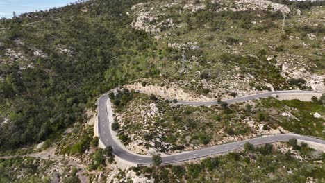 Aerial-shot-of-car-on-curvy-road-in-mountains-of-Mallorca-at-sunny-day---Road-to-Esporles-City