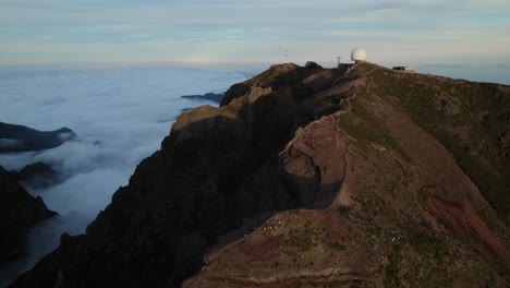 Drone-flying-over-clouds-on-the-top-of-the-mountains-at-Pico-Do-Arieiro,-Madeira-at-sunset
