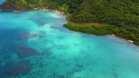 Aerial-of-turquoise-water-and-green-forest-at-Tayrona-Park,-Colombia