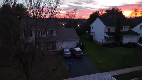 Male-delivery-man-exiting-Amazon-Prime-van-and-walking-towards-American-home-in-neighborhood-with-package-at-sunset