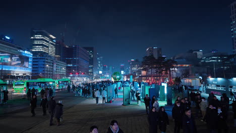 Turistas-Caminando-En-La-Plaza-Gwanghwamun-Por-La-Noche-Durante-La-Víspera-De-Navidad-Viendo-Una-Exposición-De-Arte-Digital-Al-Aire-Libre-En-Pantallas-LED