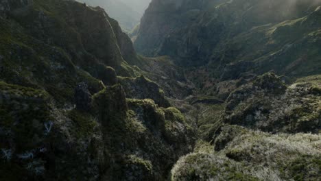 Drone-flying-in-the-mountains-at-Madeira-between-rugged-rocks-and-misty-ridgelines-during-sunrise