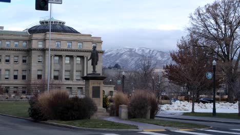 Slow-pan-of-landmark-Idaho-State-Capitol-building-and-park-grounds-with-Lincoln-statue-during-snowy-fall-season-in-Idaho,-USA