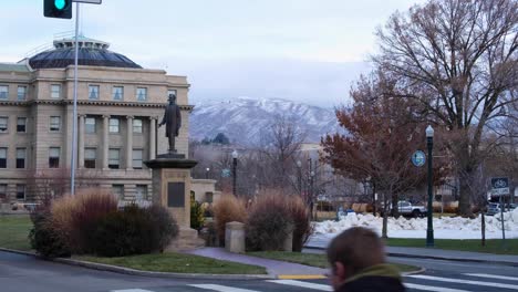 Scenic-landscape-view-of-Idaho-State-Capitol-building-and-Lincoln-statue-in-snow-covered-park-ground-with-snowcapped-mountains-in-Idaho,-USA