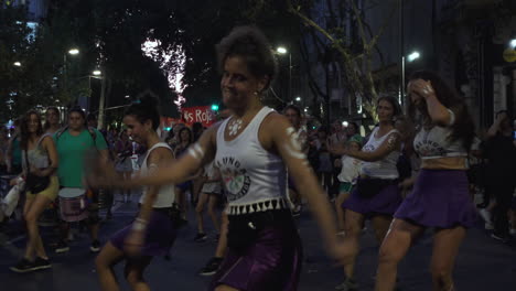 Feminist-group-with-purple-attire-march-in-protest,-they-perform-a-choreographed-dance-at-night