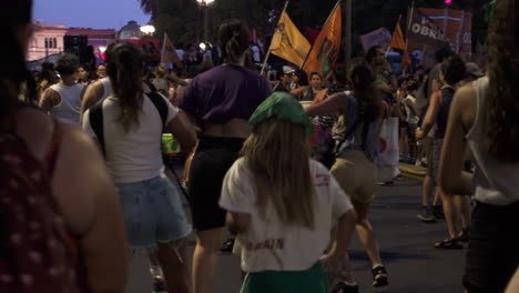 Group-of-women-and-girls-happily-perform-choreography-wearing-green,-purple-attire-in-representation-of-feminist-values-during-abortion-rally-at-night