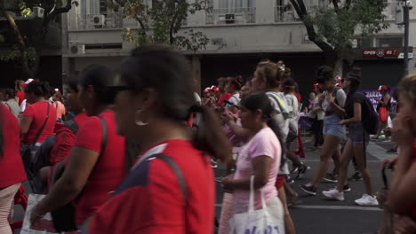 Manifestantes-Vestidos-De-Rojo-Marchan-Para-Reclamar-Sus-Derechos-En-Las-Calles-De-Buenos-Aires,-Sostienen-Carteles