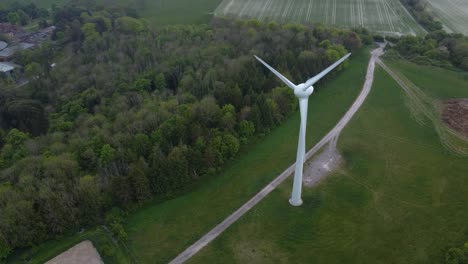 Drone-shot-of-a-wind-turbine-next-to-a-green-forest