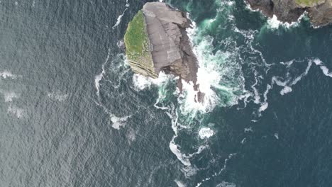 Aerial-view-cliff-meeting-the-turbulent-sea,-waves-crashing-against-the-shore
