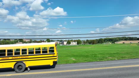 Autobús-Escolar-Amarillo-Conduciendo-En-Un-Día-Brillante-En-El-Campus-Escolar