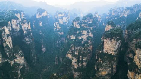 Toma-Aérea-Que-Muestra-Los-Pilares-Dentro-Del-Parque-Nacional-Zhangjiajie-Con-Aspecto-Brumoso