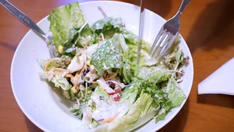 Cutting-some-salad-greens-into-smaller-bite-size-cuts-using-a-knife-and-a-fork,-in-a-restaurant-in-Bangkok,-Thailand