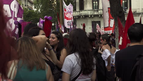 Crowd-of-young-women-gather-to-peacefully-march-with-posters-and-balloons,-they-manifest-on-the-streets-of-Buenos-Aires-during-Women's-Day-rally