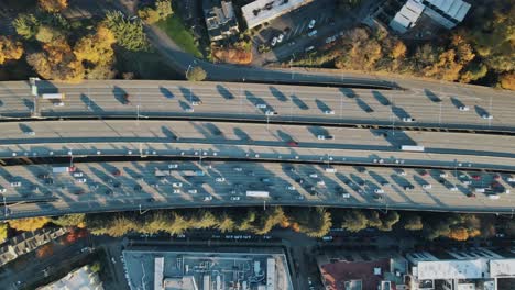 Later-afternoon-traffic-on-multi-lane-highway-congested-in-urban-city-center-during-autumn,-drone-top-down