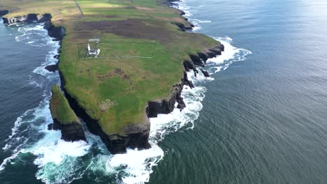 Loophead-peninsula-with-waves-crashing-against-cliffs,-clear-sky,-aerial-view