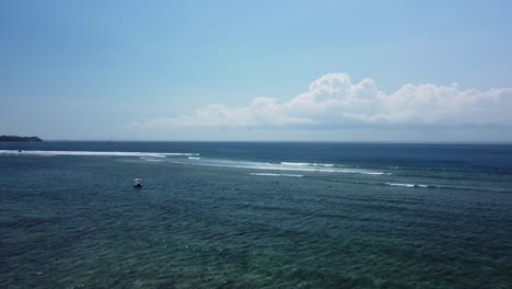 Luftwagen-über-Den-Riffebenen-Vor-Der-Küste-Von-Nusa-Lembongan-An-Einem-Atemberaubenden-Tag,-Während-Surfer-Wellen-Fangen