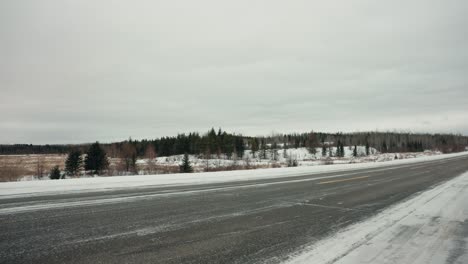 Eine-Reihe-Von-Autos,-Fahrzeugen-Und-Lastwagen-Fahren-Eine-Isolierte,-Mit-Schnee-Und-Eis-Bedeckte-Arktische-Winterlandstraße-Im-Norden-In-Der-Nähe-Von-Chruchill,-Manitoba,-Kanada-Hinunter
